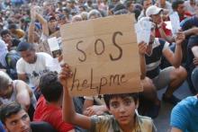 A child holds a self-made placard reading "SOS help me" outside the railways station in Budapest, Hungary, September 2, 2015. PHOTO BY REUTERS/Laszlo Balogh