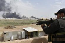 A member from the Iraqi security forces guards as smoke rises from Baiji oil refinery, north of Baghdad, Iraq, May 26, 2015. PHOTO BY REUTERS/Stringer