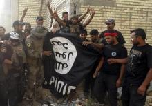 Iraqi security forces stand with an Islamist State flag which they pulled down at the University of Anbar, in Anbar province, July 26, 2015. PHOTO BY REUTERS/Stringer