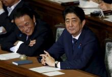Japan's Prime Minister Shinzo Abe (R) smiles with Deputy Prime Minister and Finance Minister Taro Aso during the plenary session for his cabinet's censure motion at at the Lower House of the parliament in Tokyo, Japan, September 18, 2015. PHOTO BY REUTERS/Toru Hanai