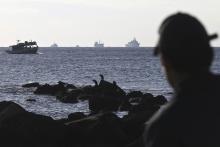 A container ship (C) is being towed by a Greek Navy frigate (2nd R) as a coast guard officer looks on, at open sea a few miles southeast from the island of Crete, November 27, 2014. PHOTO BY REUTERS/Stefanos Rapanis