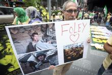 A man holds up a sign in memory of U.S. journalist James Foley during a protest against the Assad regime in Syria in Times Square in New York, August 22, 2014. PHOTO BY REUTERS/Carlo Allegri