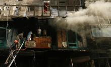 Smoke rises from the building as firefighters work to extinguish the fire at the site of a bomb attack in Peshawar