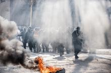 Smoke rises near the police as anti-government protesters hold a demonstration in Tuzla