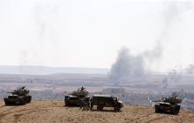Smoke rises from the Syrian town of Kobani, as Turkish army tanks take up position on the Turkish side of the border in the southeastern town of Suruc in Sanliurfa province, as seen from near the Mursitpinar border crossing on the Turkish-Syrian border