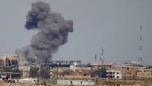A plume of smoke rises above a building during an air strike in Tikrmt, March 27, 2015. PHOTO BY REUTERS/Thaier Al-Sudani