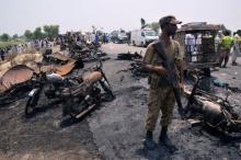 A soldier stands guard amid burnt out cars and motorcycles at the scene of an oil tanker explosion in Bahawalpur, Pakistan, June 25, 2017. PHOTO BY REUTERS/Stringer