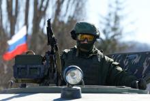 Military personnel, believed to be a Russian serviceman, stands guard on a military vehicle outside the territory of a Ukrainian military unit in the village of Perevalnoye outside Simferopol, March 3, 2014. PHOTO BY REUTERS/avid Mdzinarishvili