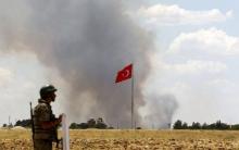 A Turkish soldier stands guard while smoke rises in the Syrian town of Kobani as it is seen from the Turkish border town of Suruc in Sanliurfa province, Turkey, June 26, 2015. PHOTO BY REUTERS/Murad Sezer