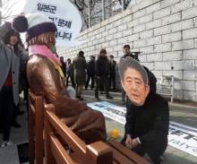 A man wearing a mask of Japanese Prime Minister Shinzo Abe kneels down in front of a statue of a girl that represents the sexual victims by the Japanese military during a rally in front of Japanese Consulate in Busan, South Korea, January 4, 2017. PHOTO BY REUTERS/Kim Sun-ho