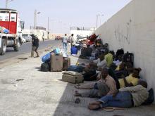 Sudanese workers rest on the ground as they wait for Egyptian visas, next to the Libyan-Egyptian border crossing in Musaid