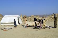 Survivors of an earthquake prepare to fix makeshift tents for shelter near the rubble of a mud house after it collapsed following the quake at Dhallbedi Peernder village in Awaran district
