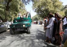 A Taliban (R) stands as Afghan security forces ride on an army vehicle during celebration ceasefire in Bati Kot district of Nangarhar province, Afghanistan, June 16, 2018. PHOTO BY REUTERS/Parwiz