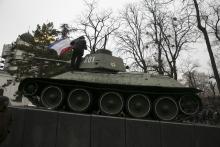 An ethnic Russian Ukrainian man holds the Crimea flag on top of an old Soviet tank during rallies near the Crimean parliament building in Simferopol