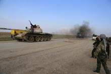 A military tank is driven past Kurdish People's Protection Units (YPG) and Kurdistan Workers Party (PKK) fighters manning a checkpoint on a highway connecting the Iraqi-Syrian border town of Rabia and the town of Snuny, north of Mount Sinjar, December 20, 2014. PHOTO BY REUTERS/Massoud Mohammed