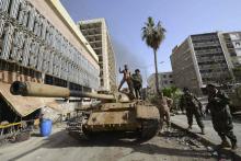 Members of the Libyan pro-government forces, backed by locals, gather on a tank outside the Central Bank, near Benghazi port, January 21, 2015. PHOTO BY REUTERS/Esam Omran Al-Fetori 