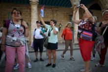 A tour guide (C) raises a Cuban national flag to regroup foreign visitors she is taking through Old Havana, March 16, 2016. PHOTO BY REUTERS/Alexandre Meneghini