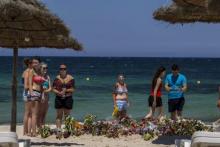 Tourists pay their respects in front of flowers laid out along a beachside in memory of the victims killed by a gunman at the Imperial Marhaba resort, in Sousse, Tunisia, July 1, 2015. PHOTO BY REUTERS/Zohra Bensemra