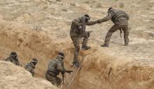 Tunisian soldiers participating in an exercise climb out of a trench, that forms part of a barrier along the frontier with Libya in Sabkeht Alyun,Tunisia, February 6, 2016. PHOTO BY REUTERS/Zoubeir Souissi