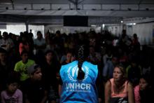 A member of United Nations High Commissioner for Refugees (UNHCR) talks with Venezuelans as they queue in line to receive a vaccine after showing their passports or identity cards at the Pacaraima border control, Roraima state, Brazil, August 8, 2018. PHOTO BY REUTERS/Nacho Doce