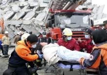 Rescue personnel help a victim at the site where a 17-storey apartment building collapsed during an earthquake in Tainan, southern Taiwan, February 6, 2016. PHOTO BY REUTERS/Patrick Lin