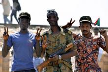 A Sudanese military officer and demonstrators gesture in celebration after Defence Minister Awad Ibn Auf stepped down. PHOTO BY REUTERS/Stringer
