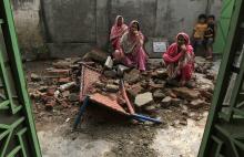 Villagers sit on the debris of their house after it was damaged during the recent exchange of fire between Pakistan and India at the Pakistani border town of Dhamala Hakimwala near Sialkot