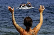 A volunteer signals at a dinghy with Afghan migrants at a beach on the Greek island of Lesbos, after the dinghy crossed a part of the Aegean Sea from the Turkish coast, September 21, 2015. PHOTO BY REUTERS/Yannis Behrakis