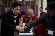 Polling officers help a Tibetan monk (C) to cast his vote during the election for the Tibetan government-in-exile at a polling booth in Dharamsala, India, March 20, 2016. PHOTO BY REUTERS/Adnan Abidi