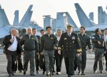 Japan's Prime Minister Shinzo Abe (C), Deputy Prime Minister and Finance Minister Taro Aso (2nd R) and Defence Minister Gen Nakatani (2nd L) walk with Chris Bolt, the captain of the USS Ronald Reagan, a Nimitz-class nuclear-powered super carrier, as they visit the aircraft carrier at Sagami Bay, off Yokosuka, south of Tokyo, October 18, 2015. PHOTO BY REUTERS/Kyodo