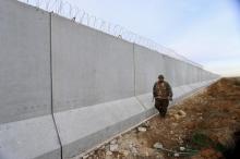 A Kurdish People's Protection Units (YPG) fighter walks near a wall, which activists said was put up by Turkish authorities, on the Syria-Turkish border in the western countryside of Ras al-Ain, Syria, January 29, 2016. PHOTO BY REUTERS/Rodi Said