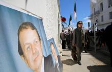 A woman walks past posters of Algerian President Abdelaziz Bouteflika in Algiers, Algeria, April 9, 2018. PHOTO BY REUTERS/Ramzi Boudina