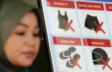 A woman walks past a sign with information about a dress code outside a government building in Kuala Lumpur, Malaysia, July 15, 2015. PHOTO BY REUTERS/Olivia Harris