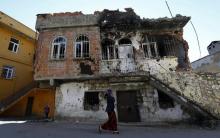 A woman walks past a building which was damaged during the security operations and clashes between Turkish security forces and Kurdish militants, in the southeastern town of Silvan in Diyarbakir province, Turkey, December 7, 2015. PHOTO BY REUTERS/Murad Sezer