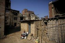 A woman washes cloths as she sits outside her temporary shelter built near the houses damaged during an earthquake earlier this year, in Bhaktapur, Nepal, December 28, 2015. PHOTO BY REUTERS/Navesh Chitrakar