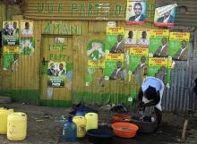 A woman washes her clothes by a wall with various campaign posters in the Kibera slum in Nairobi, March 3, 2013. PHOTO BY REUTERS/Noor Khamis
