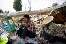 Migrant workers Wang Qin (L) and her sister Wang Jun eat lunch during a break from collecting scrap materials from the debris of demolished buildings at the outskirts of Beijing, China, October 1, 2017. PHOTO BY REUTERS/Thomas Peter