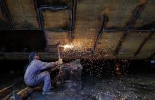 A worker repairs a vessel at a ship repair yard in Mumbai