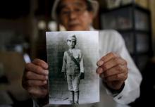 Yoshiteru Kohata, a 86-year-old Nagasaki atomic bombing survivor and retired school teacher, who returned to his home region of Fukushima after World War Two, poses with a portrait taken when he was in middle school, at his home in the town of Miharu, Fukushima Prefecture, Japan, July 31, 2015. PHOTO BY REUTERS/Toru Hanai